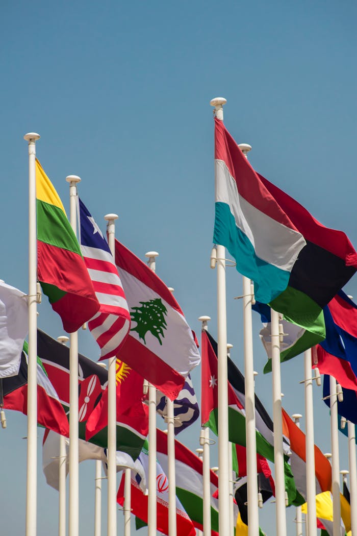 A vibrant array of international flags waving against a clear blue sky, symbolizing global unity.