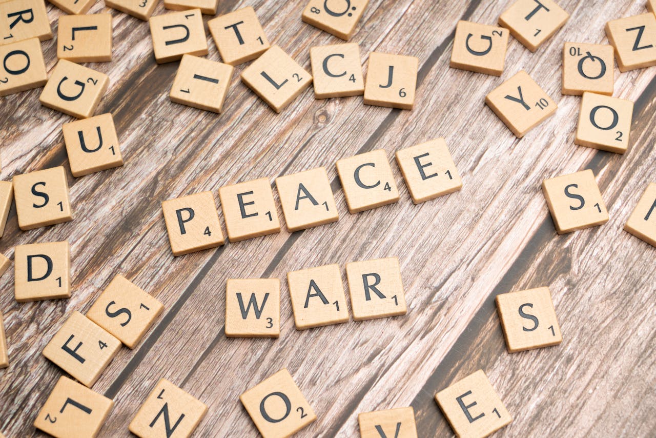 Wooden letter tiles spelling 'PEACE' and 'WAR' on a rustic surface.